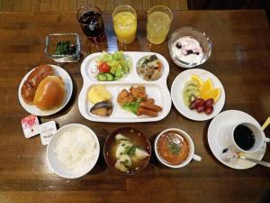 a wooden table with plates of food and drinks at Southern Cross Inn Matsumoto in Matsumoto