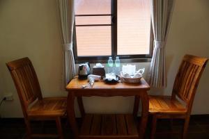 une table en bois avec deux chaises et une fenêtre dans l'établissement Ruean Phet Sawoei Resort, à Phutthaisong