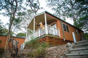 una persona de pie en el porche de una casa pequeña en Discovery Parks - Lane Cove, en Sídney