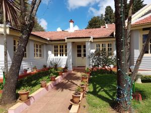 a white house with trees and plants in a yard at KSTDC Hotel Mayura Sudarshan ,Ooty in Ooty