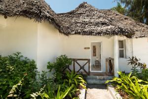 a small white house with a thatched roof at Driftwood Beach Lodge in Jambiani