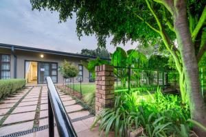 a house with a fence and a tree at Murray Street 137 Guesthouse in Pretoria