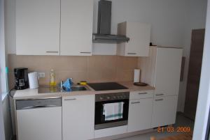 eine Küche mit weißen Schränken und einem Herd mit Backofen in der Unterkunft Monteurzimmer-Apartment Scholl Pforzheim in Pforzheim