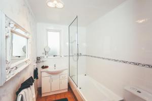 La salle de bains blanche est pourvue d'un lavabo et d'une douche. dans l'établissement Lexington Park Cottages, à Cambridge