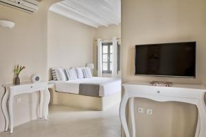 a white bedroom with a bed and a flat screen tv at Carpe Diem Santorini in Pyrgos