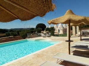 - une piscine avec un parasol et des chaises dans l'établissement Tramonti d'Itria, à Ostuni