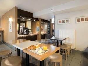 a restaurant with a table with a plate of food on it at B&B HOTEL Grenoble Université in Gières