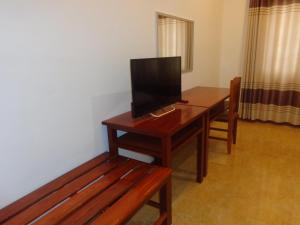 Habitación con escritorio de madera y TV. en Phouluang Hotel, en Phonsavan