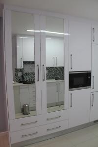 a white kitchen with white cabinets and a microwave at Pat Luxurious Studio in Gaborone
