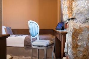 a room with a chair and a desk with a laptop at Hôtel West End Promenade in Nice