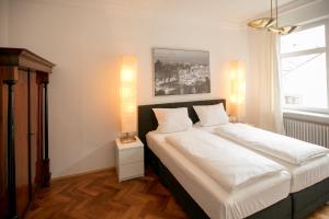 a bedroom with a bed with white sheets and a window at Palazzo am Dom in Regensburg