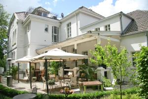 ein großes weißes Haus mit Tischen und Sonnenschirmen in der Unterkunft Hotel Hochzeitshaus in Aurich