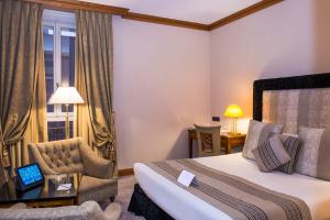 a hotel room with a bed and a chair and a window at Hôtel West End Promenade in Nice