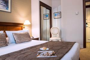a hotel room with a bed with a plate of food on it at Hôtel West End Promenade in Nice