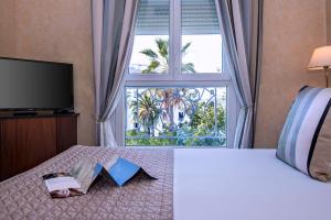 a bedroom with a bed with a large window at Hôtel West End Promenade in Nice