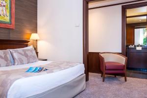 a hotel room with a bed and a chair at Hôtel West End Promenade in Nice