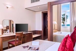 a hotel room with a desk and a bedroom at Hôtel West End Promenade in Nice