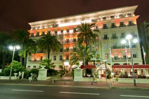 a large building with palm trees in front of it at Hôtel West End Promenade in Nice