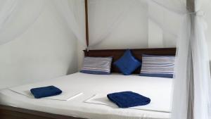 Una cama con dos almohadas azules. en Calidan, en Mirissa