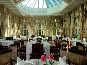 a dining room with tables and chairs and a skylight at Tylney Hall Hotel in Hook