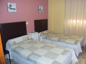 two beds in a room with a white bedspread at La Esteponera in La Línea de la Concepción