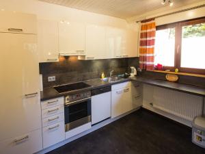 cocina con armarios blancos, fregadero y ventana en Ferienwohnung am Hauskopf, en Oppenau