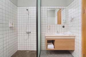 a bathroom with a sink and a shower and a mirror at Mogens Guesthouse in Bandung