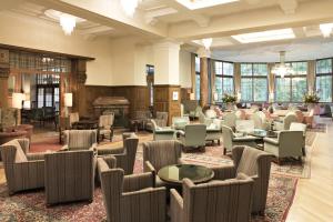 eine große Lobby mit Stühlen, Tischen und Fenstern in der Unterkunft Hotel Waldhaus Sils in Sils Maria