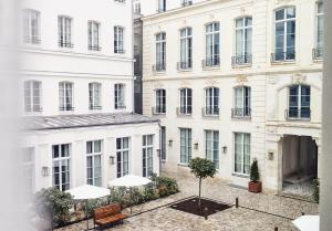 a group of white buildings with a bench and trees at The Hoxton, Paris in Paris