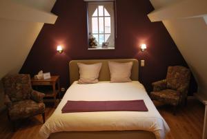 a bedroom with a bed with two chairs and a window at Bed & Breakfast Esprit de Mer in De Panne