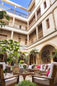 une cour avec des chaises et des tables et un bâtiment dans l'établissement Riad Chbanate, à Essaouira