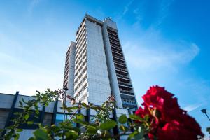 un grand bâtiment avec une rose rouge devant lui dans l'établissement Hotel Arpezos, à Kardjali