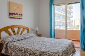 ein Schlafzimmer mit einem Bett und einem großen Fenster in der Unterkunft Apartamentos Zambra III in La Manga del Mar Menor