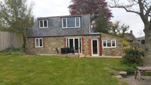 Casa de ladrillo con ventanas blancas y patio en Mallows Byre, en Sherborne