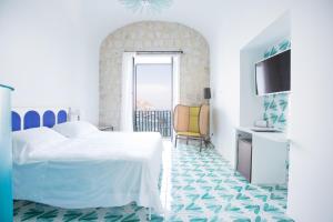 a white bedroom with a bed and a chair at Miramare Sea Resort & Spa in Ischia