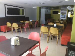 a dining room with tables and chairs and a tv at Hotel 56 Avenue Plaza in Barranquilla