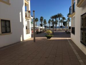 an empty street with palm trees and buildings at La Puntica Carboplaya in Carboneras