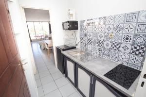 a kitchen with a sink and tiles on the wall at Apt 5 min à pied centre ville in Saint-Gilles-les-Bains