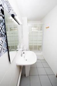 a white bathroom with a sink and a mirror at Apt 5 min à pied centre ville in Saint-Gilles-les-Bains