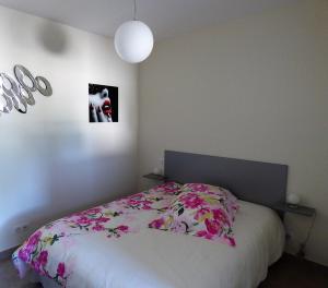 Un dormitorio con una cama con flores rosas. en AU GRAIN D'ORGE en Échiré