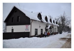 um edifício coberto de neve com pessoas do lado de fora em Penzion Severák em Rokytnice v Orlickych Horách