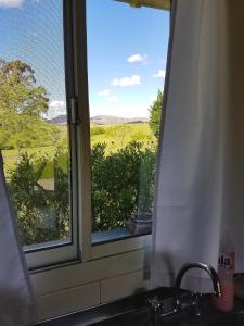 a window over a sink with a view of a field at Cabañas Arcángeles de Tandil in Tandil