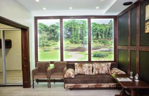 een kamer met een groot raam met een bank en stoelen bij Nashe Misto Guest House in Kovel