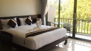 a bedroom with a bed with white sheets and a balcony at Amarina Green in Lamai