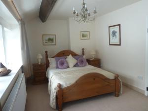 a bedroom with a wooden bed with purple pillows at Royds Hall Cottage in Keighley