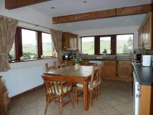 a kitchen with a wooden table and some windows at Royds Hall Cottage in Keighley