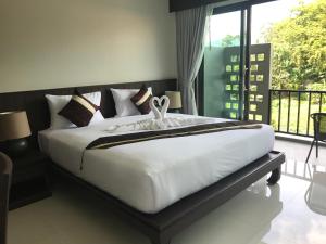 a bedroom with a large white bed with a balcony at Amarina Green in Lamai