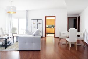 a living room with white furniture and a table at Parque das Nações - Fil New Apartment in Lisbon