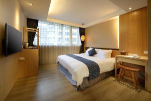 una camera d'albergo con letto, scrivania e TV di Yunoyado Onsen Hot Spring Hotel -Xinyi Branch a Jiaoxi