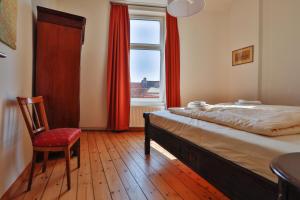 ein Schlafzimmer mit einem Bett, einem Stuhl und einem Fenster in der Unterkunft Riverside Apartments in Lübeck